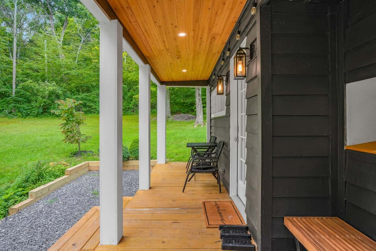 Porch corner under the cedar ceiling, with a wall lantern and the black board-and-batten siding