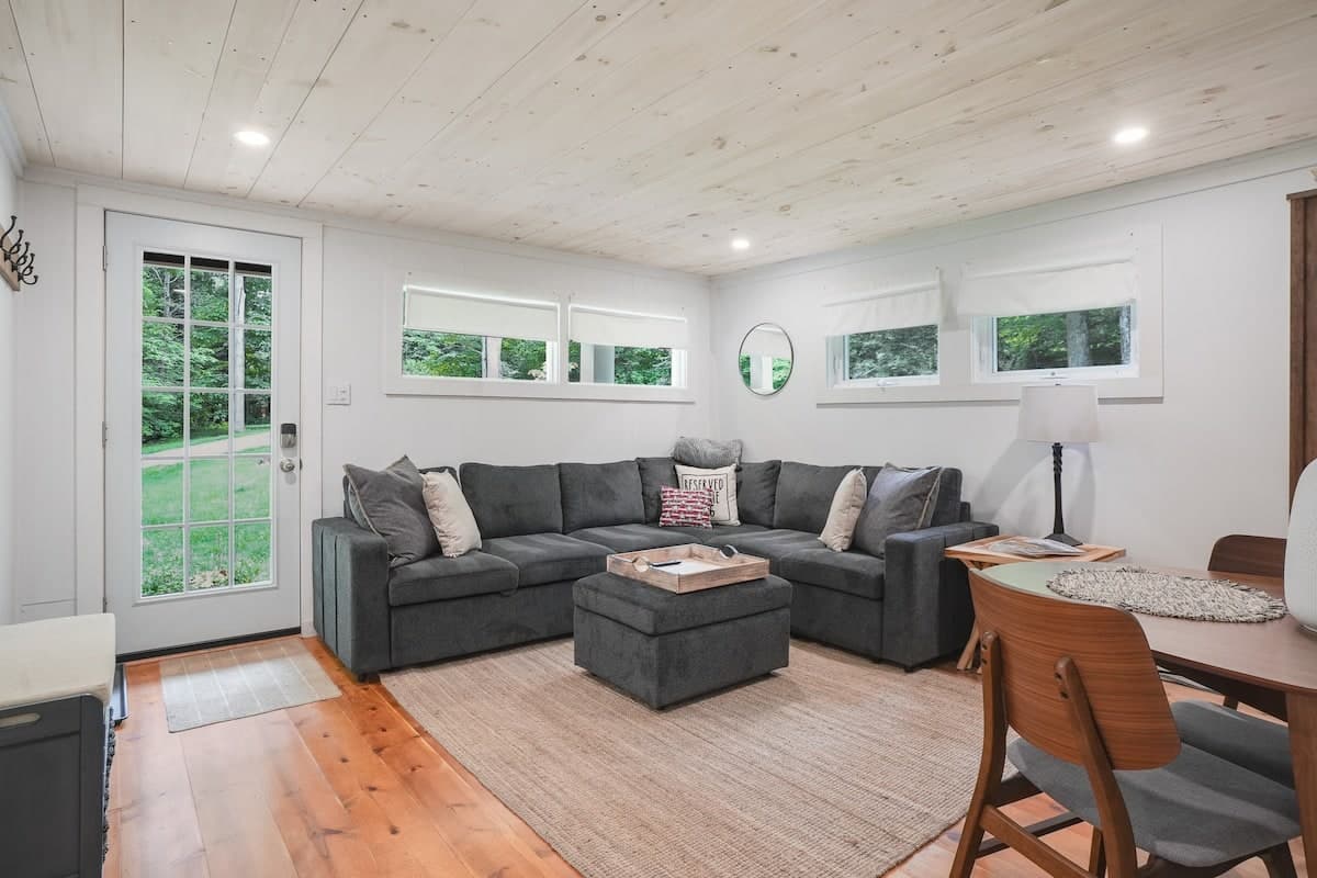 The sectional under a run of clerestory windows, with the glass door to the deck standing open