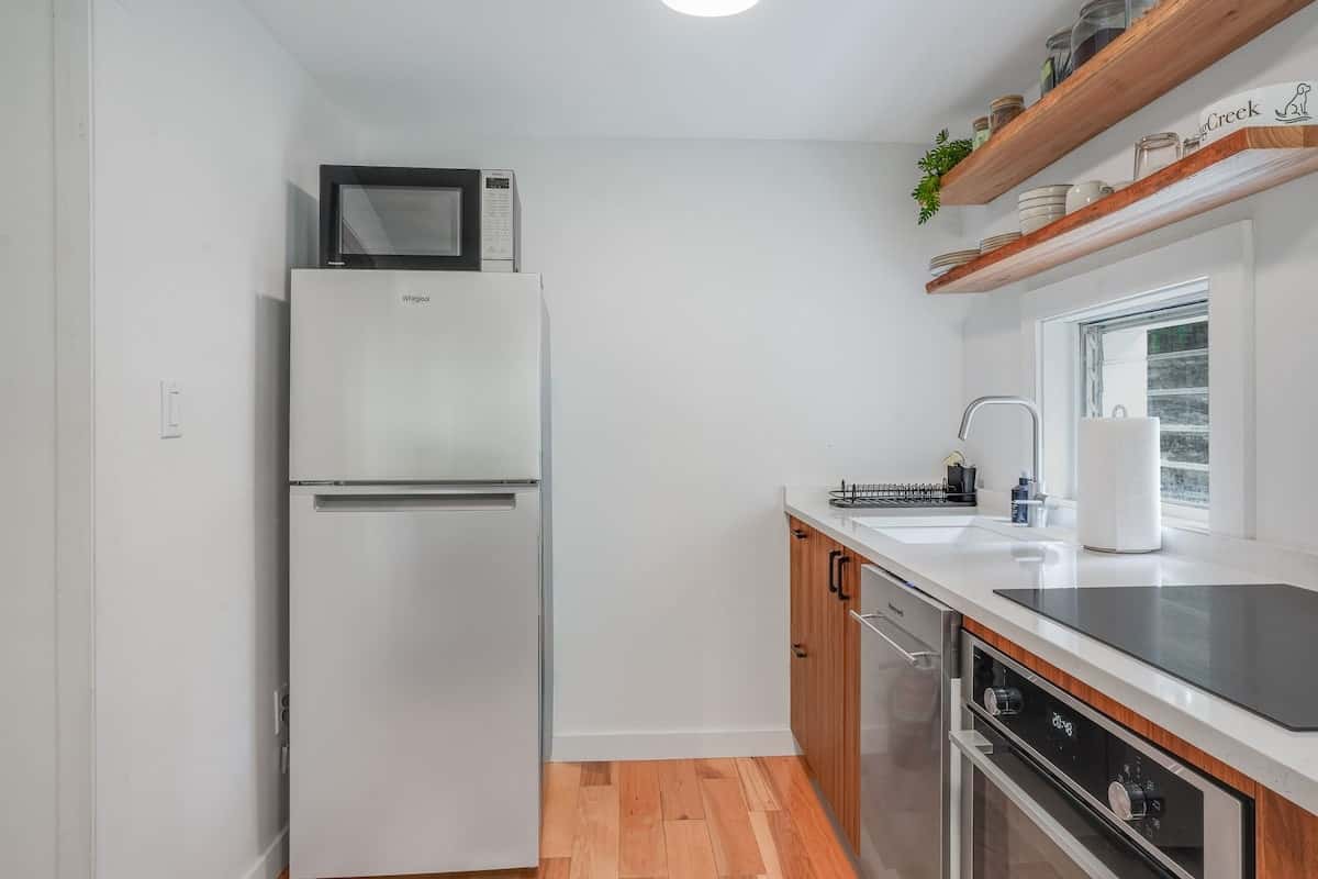 The kitchen: full-size refrigerator, dishwasher, and electric cooktop beneath open cherry-toned cabinets
